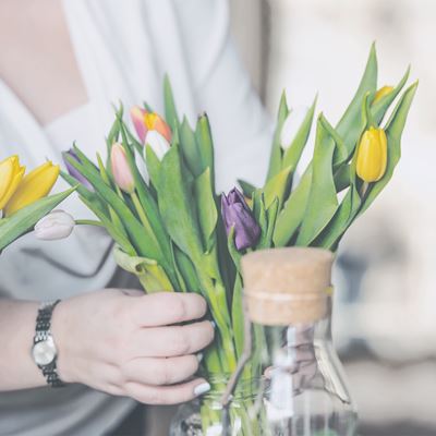 En dame sætter en buket tulipaner i vase