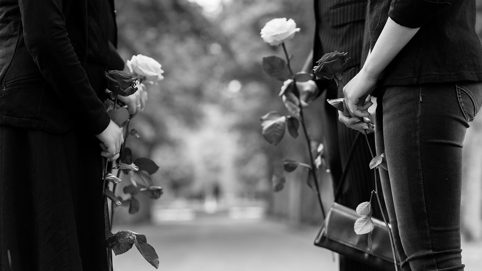 En familie står med roser på en kirkegård